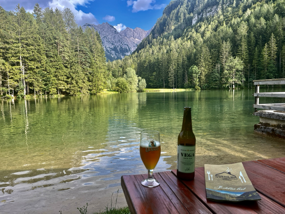Bergpanorama gespiegelt im See mit einem Bierglas und Bierflasche ganz vorne 