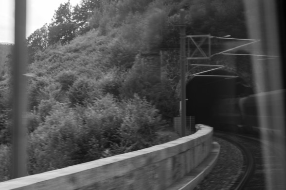black and white picture of a train entering a tunnel. 