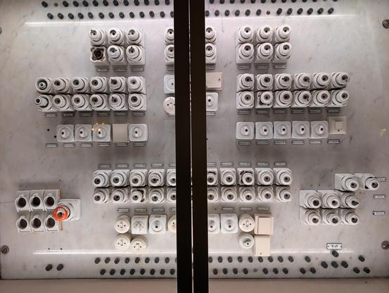 uralte Elektrische Sicherungen und Schalter mit cooler Beleuchtung von oben und alten Beschriftungen auf Emailplättchen