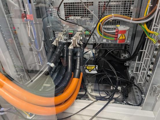 mehrere ca. 3cm dicke orangene und schwarze Stromkabel führen zu zwei entsprechend ausgestatteten Anschlüssen