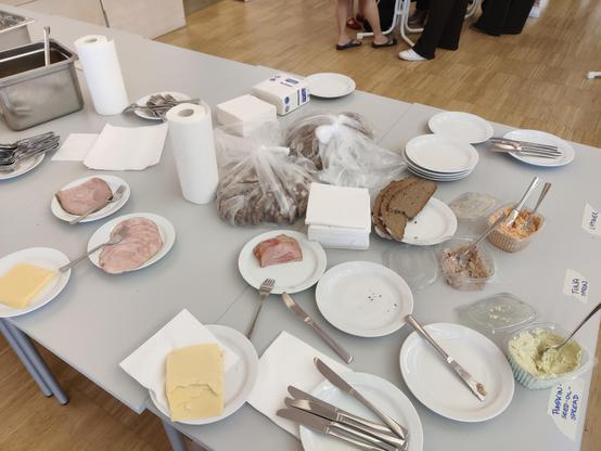 Ein Buffett Tisch mit Resten von Wurst, Käse, Aufstreichen und Brot.