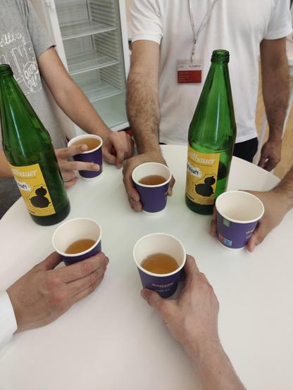 Stehtisch, auf dem 5 Becher Apfelsaft gehalten werden