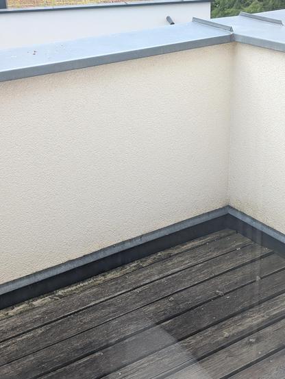 Reste eines Wespennests, das im Eck innen unter der Metallabdeckung gebaut wurde liegen am Holzboden verstreut. Irritierte Wespen fliegen um das alte Nest als auch über den Bruchstücken. 