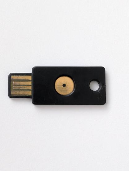 The Yubico YubiKey token from above on a white surface. The USB pins are a bit worn. The rest seems OK.